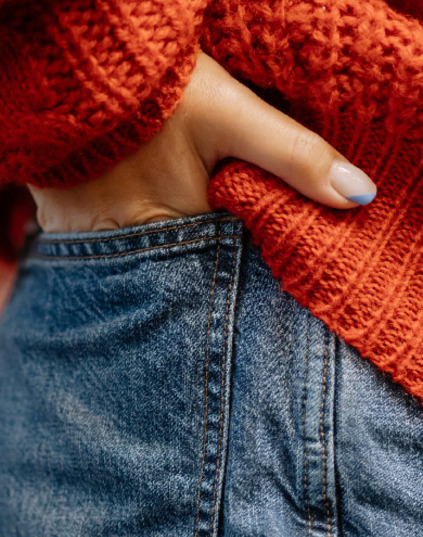 woman wearing denim jeans with organe sweater hands in the pocket