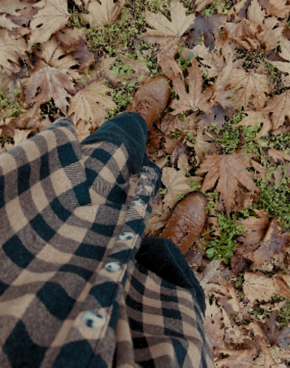 woman in classics tartan skirt walking on leaves in the autumn forest